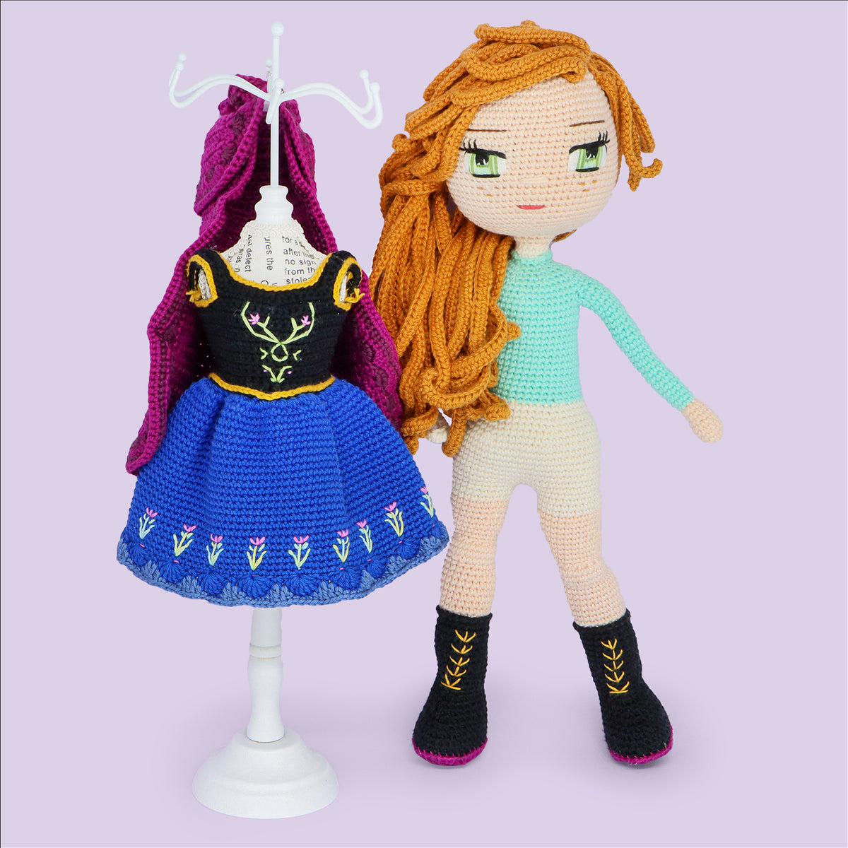 Scottish Princess amigurumi doll with wavy red hair beside her blue dress and cape on a mini mannequin