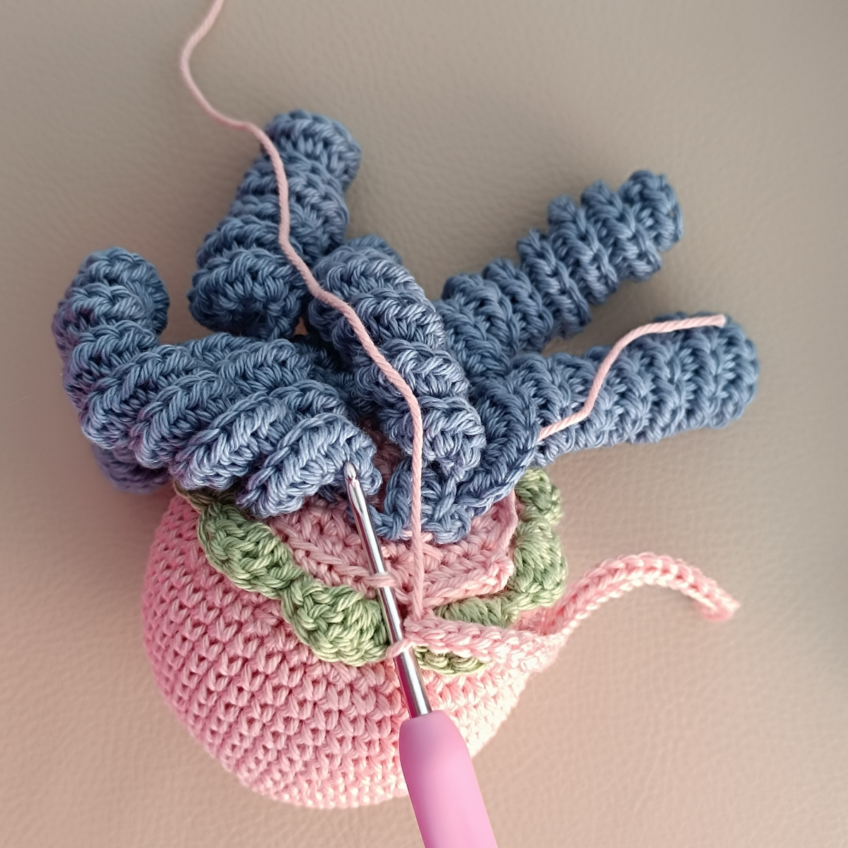 Attaching blue curly tentacles to the pink jellyfish body with a crochet hook - amigurumi course lesson