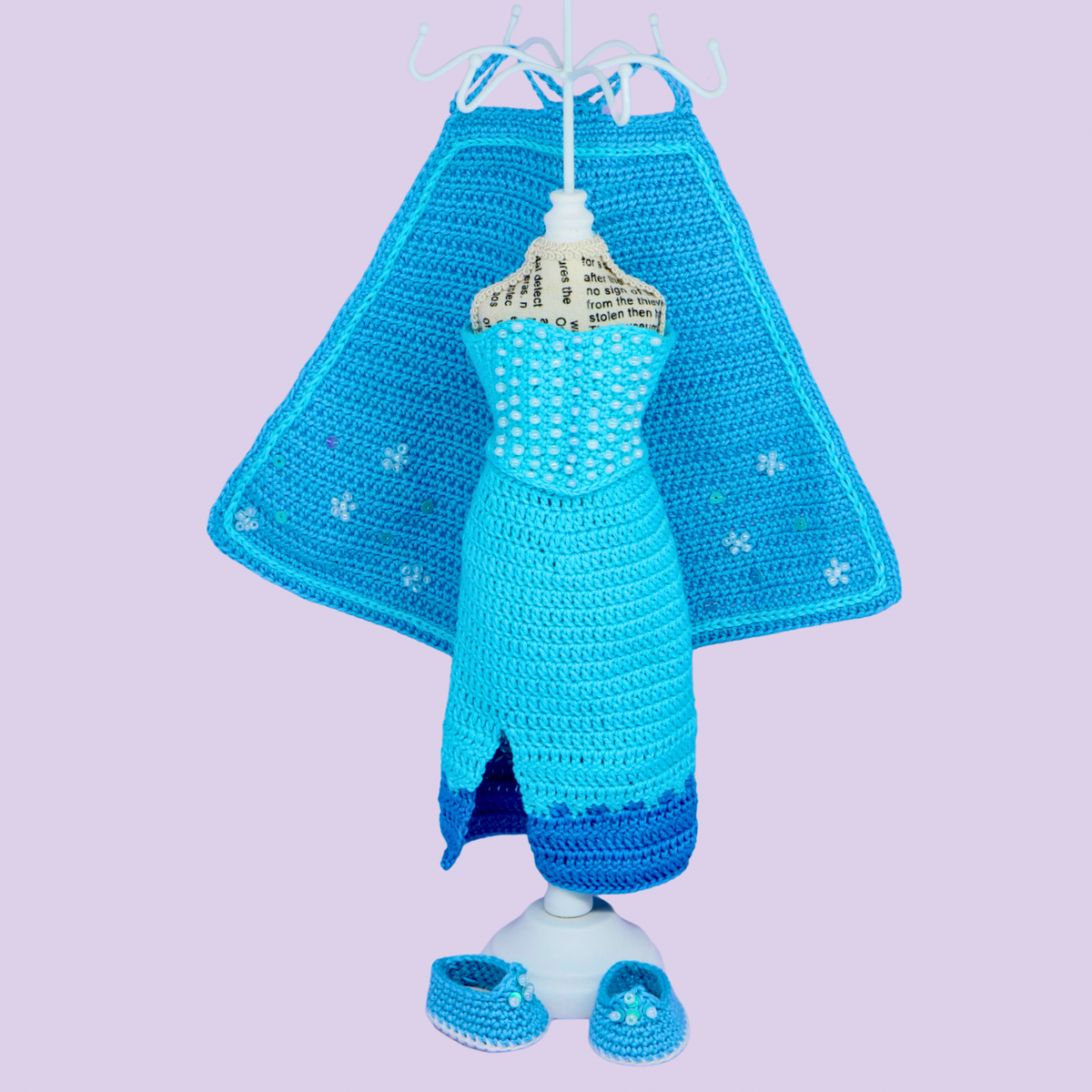 Snow Queen crochet outfit - ice blue dress with snowflake cape and little shoes displayed on doll stand