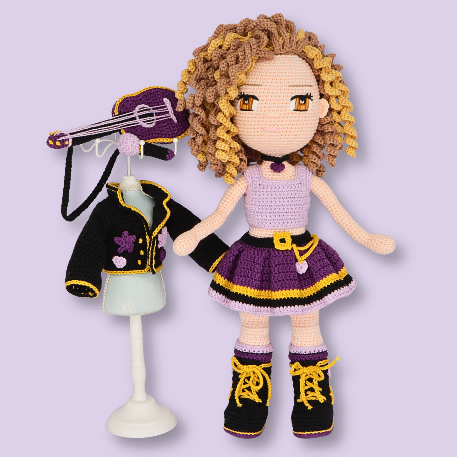 Alice amigurumi doll next to her removable black jacket and guitar on a doll stand - crochet pattern