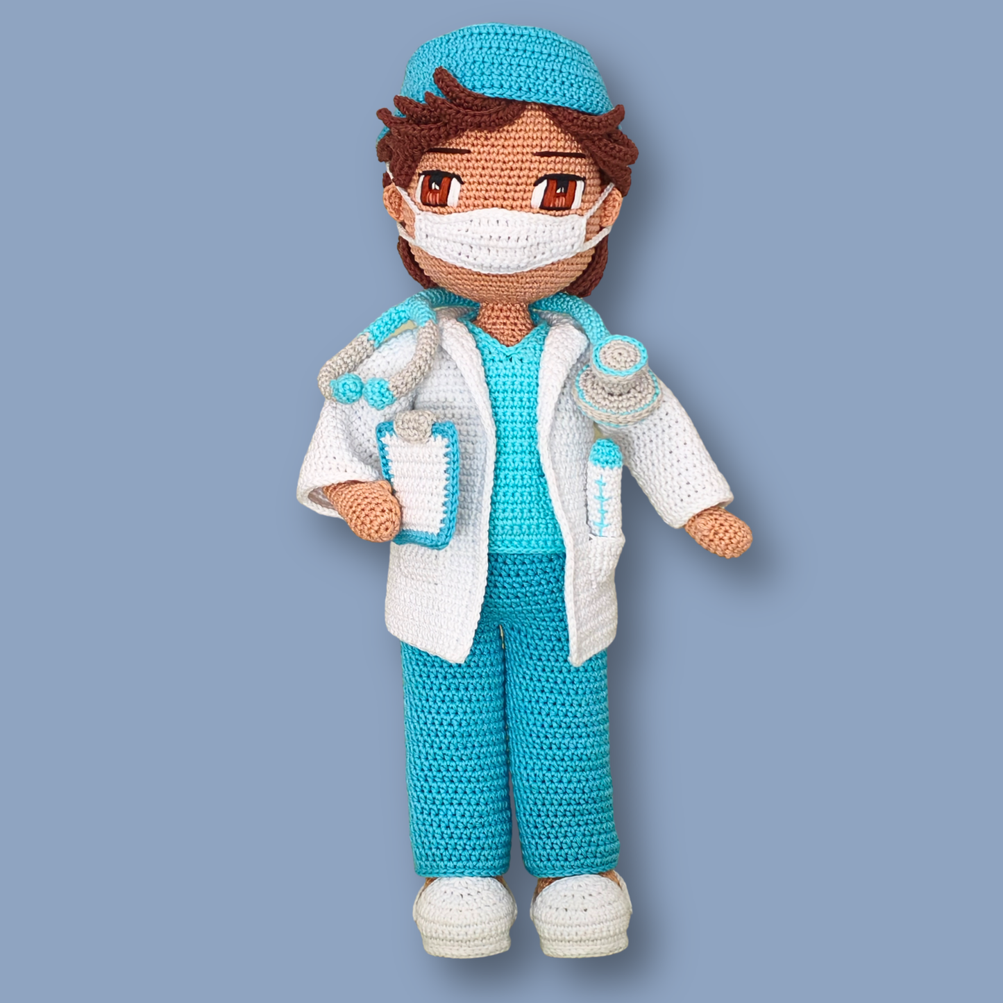 Dr. Thomas amigurumi doll wearing a face mask and scrub cap, with clipboard and syringe in lab coat pockets