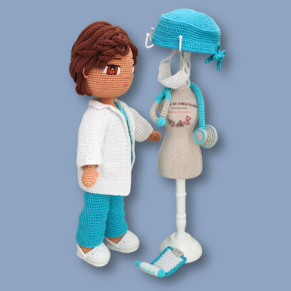 Side view of Dr. Thomas amigurumi doll facing a mini mannequin with scrub cap, face mask, and clipboard