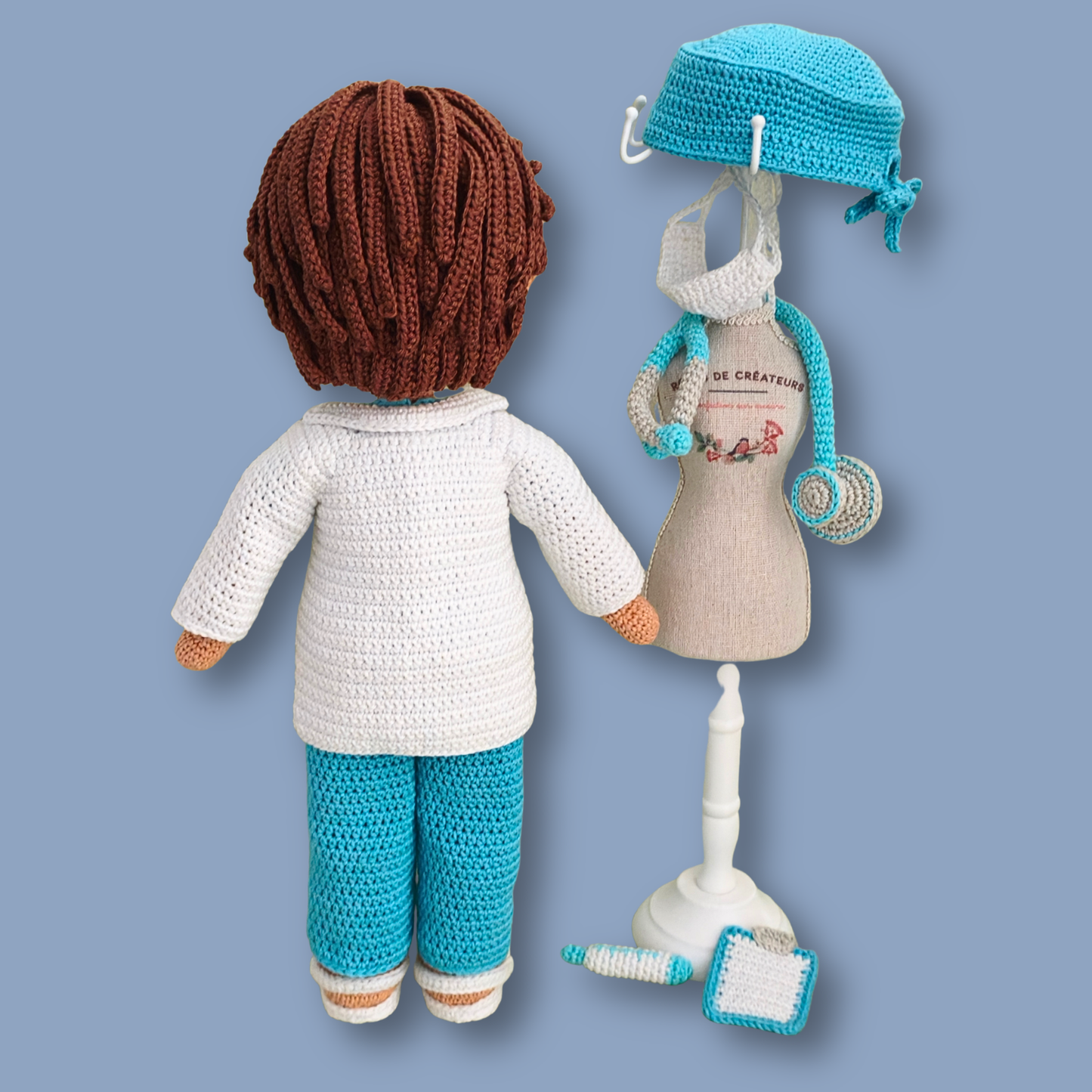 Back view of Dr. Thomas crochet doll showing brown hair, with doctor accessories displayed on a doll mannequin