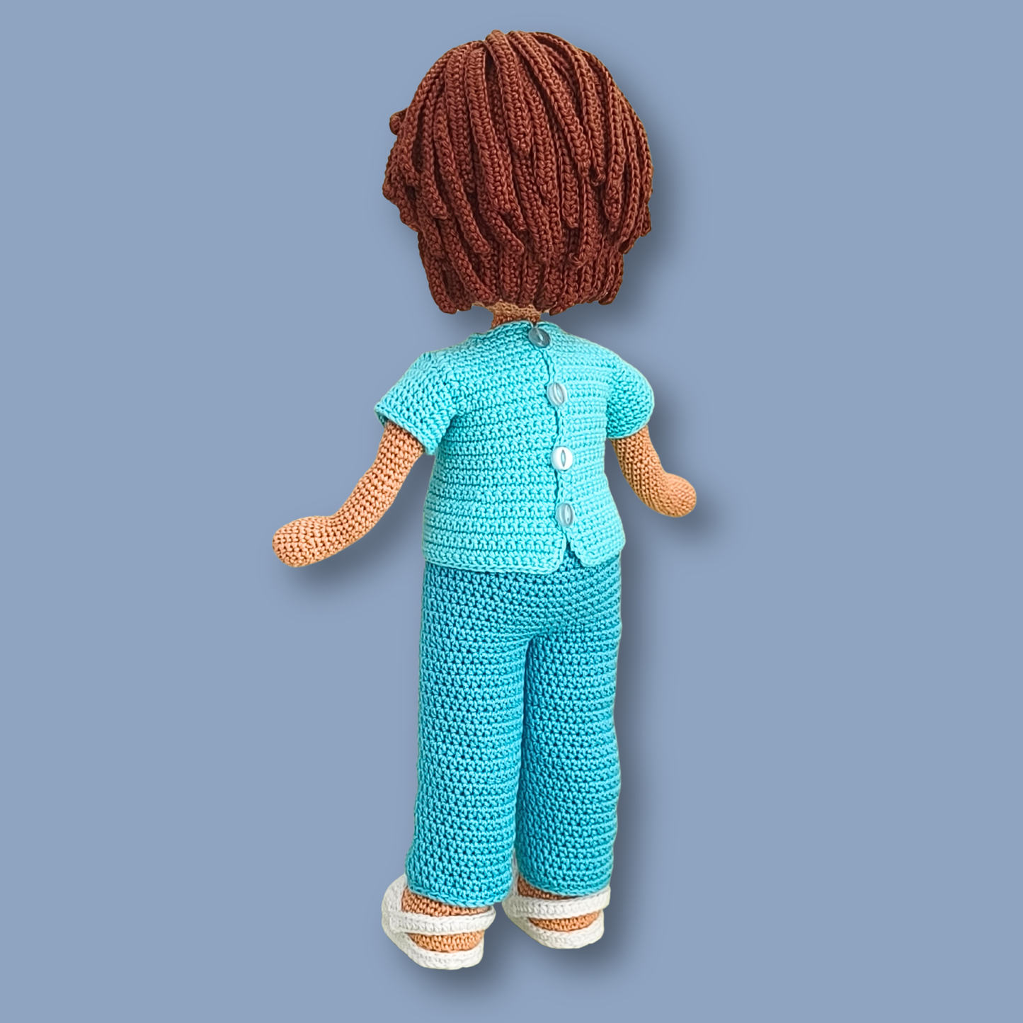Back view of Dr. Thomas amigurumi doll showing the button closure on the turquoise scrub top
